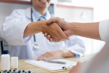 Medical professionals shaking hands across desk
