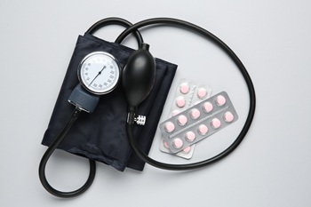 Blood pressure measuring device and pills on gray background.